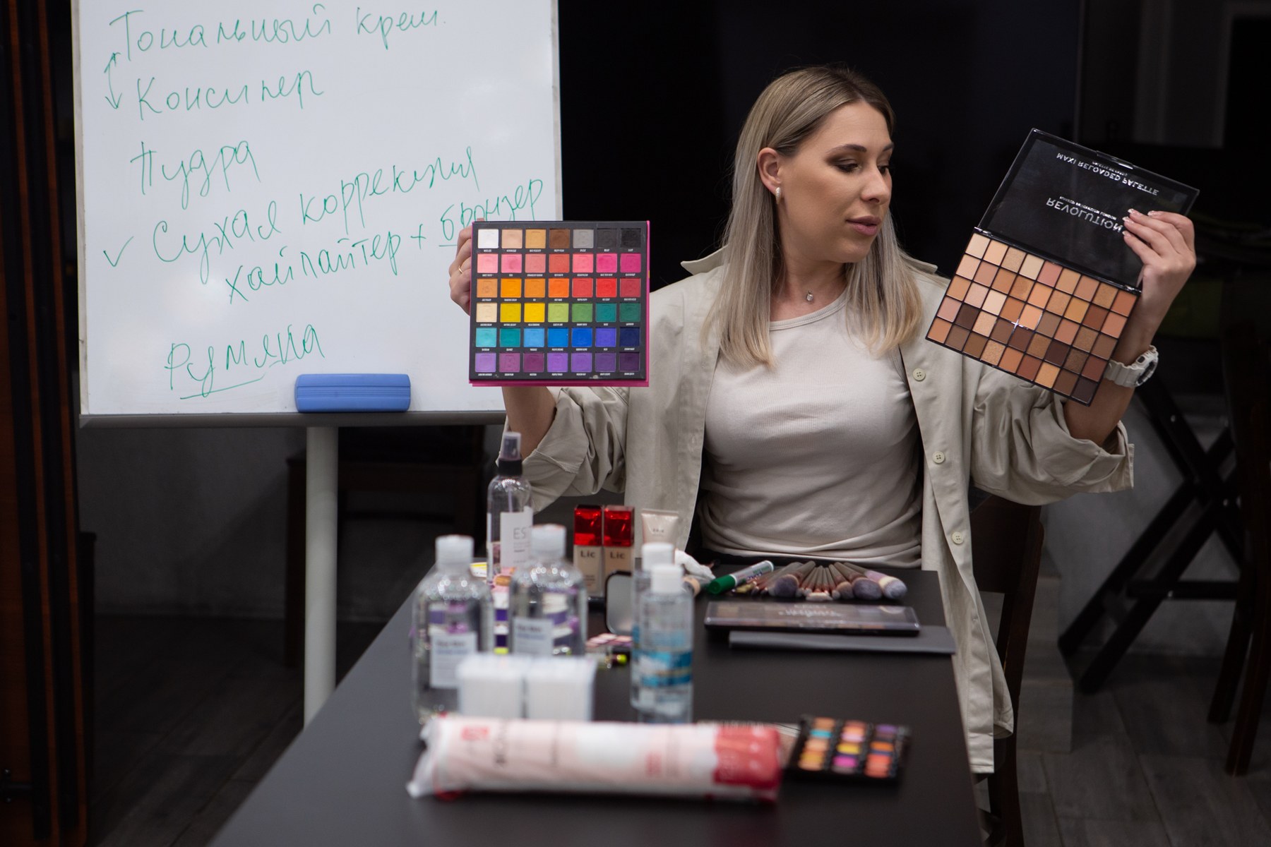 Makeup instructor comparing a colorful eyeshadow palette with a neutral face palette