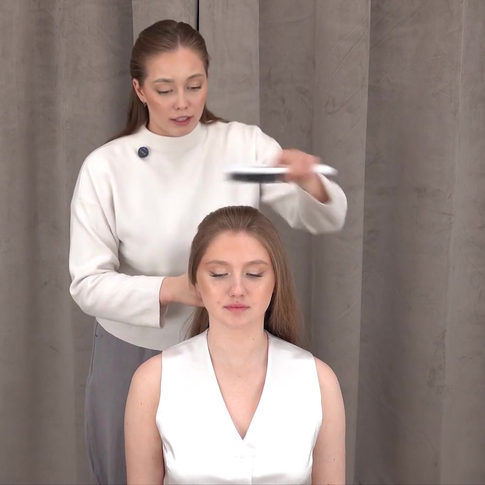 La instructora cepilla el cabello de la modelo hacia atrás antes de hacer una coleta alta