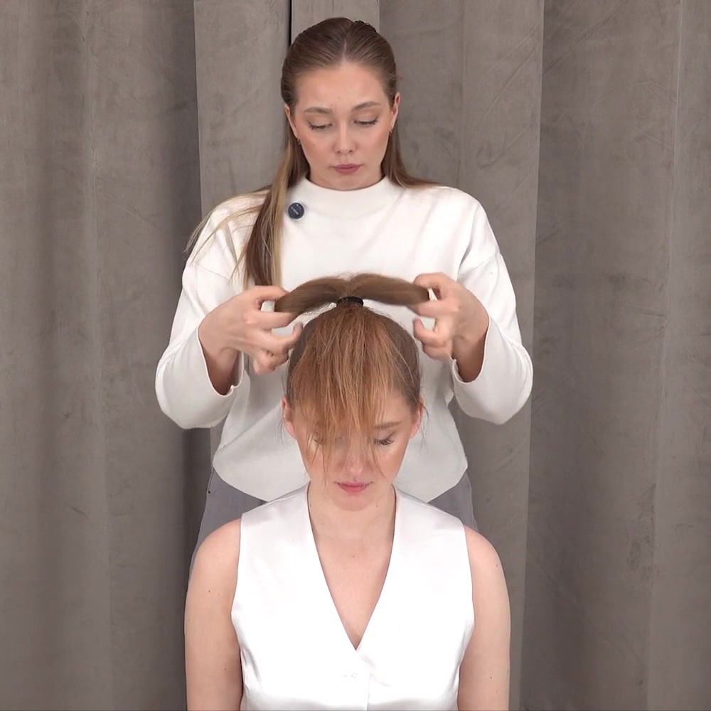 La instructora separa el cabello doblado en los dos lados del lazo
