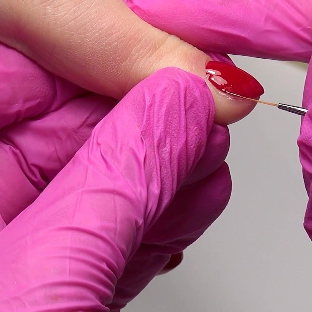Un cepillo de detalle fino refina la segunda capa de gel polish cerca del lado de la uña