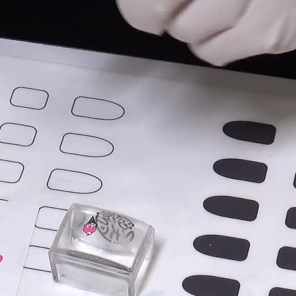 A fine nail-art brush fills the back of an ice cream outline with pink stamping polish