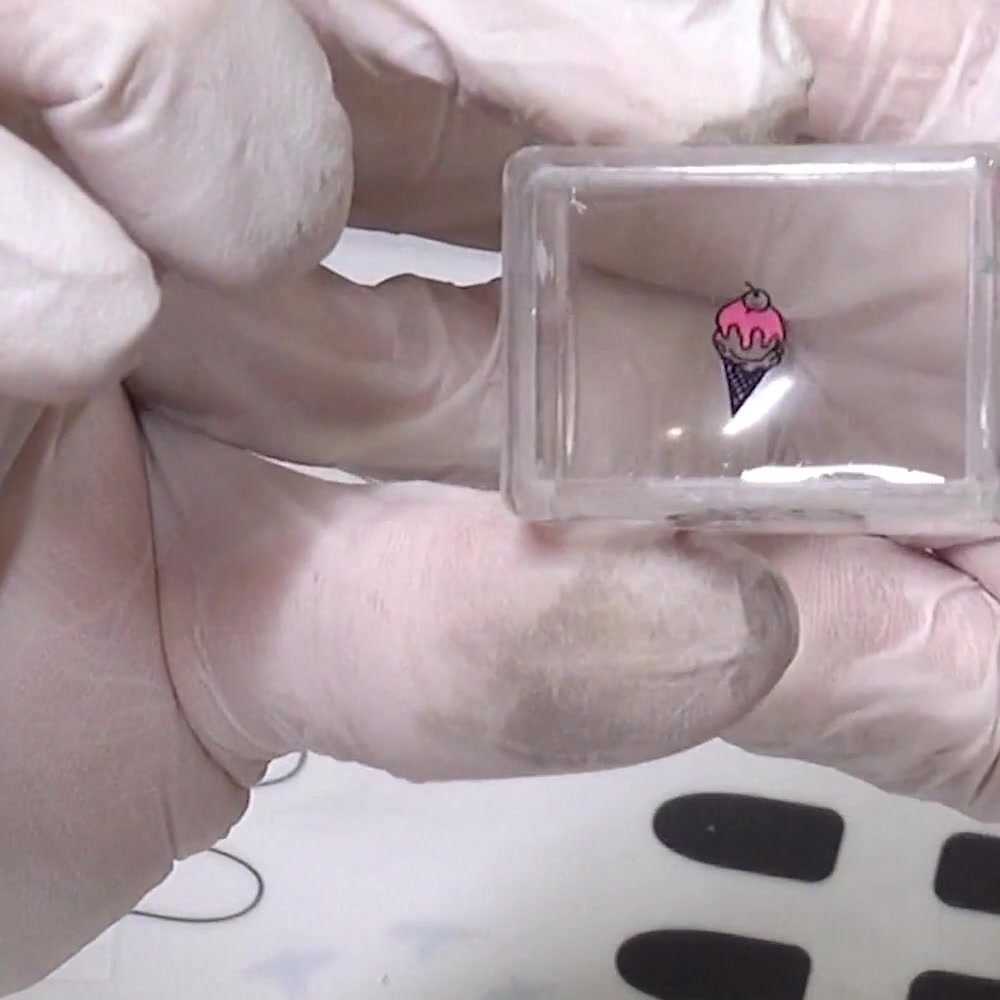 The finished pink and purple ice cream design is inspected through the clear stamper